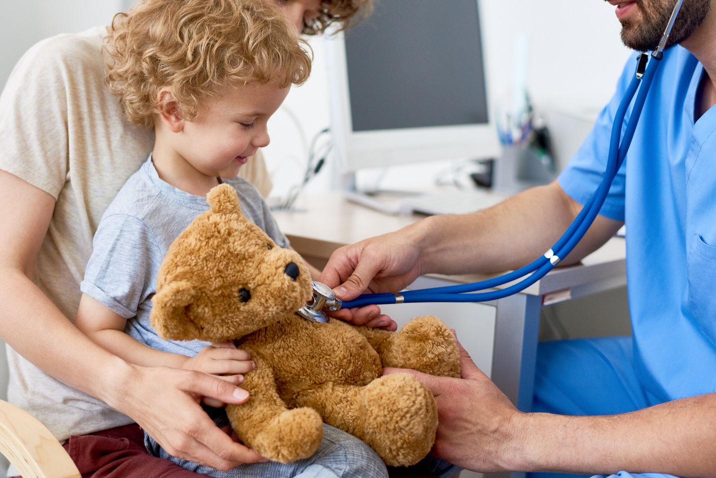 child holding teddy bear toy with pediatrician listening to heartbeat using stethoscope